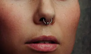 Zbliżenie na twarz z piegami i kolczykiem w nosie. Ile goi się septum? To pytanie zadaje sobie wiele osób decydujących się na ten rodzaj piercingu.