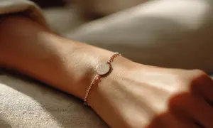 Dłoń z delikatną bransoletką z okrągłą zawieszką z grawerem.