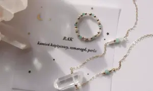 Biżuteria z kamieniami dla Raka: naszyjnik z kryształem i bransoletka z pereł, szmaragdu i złotych kuleczek.