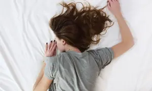 Kobieta śpi na boku, dbając o komfortowe pozycje, by ułatwić gojenie po przekłuciu uszu.