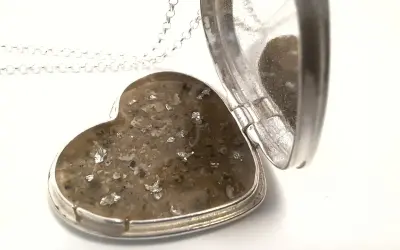 Srebrne serce-medalion z zawartością prochów, przypominające diament z prochów.