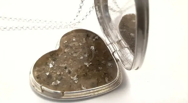 Srebrne serce-medalion z zawartością prochów, przypominające diament z prochów.