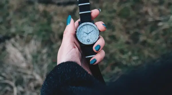 Dłoń z turkusowymi paznokciami trzyma zegarek z czarną bransoletką. Zastanawiasz się, czym wyczyścić bransoletkę od zegarka?