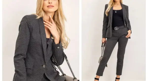 Elegancki damski casual dress code: kobieta w grafitowym garniturze w drobny wzór, z czarną bluzką i torebką.