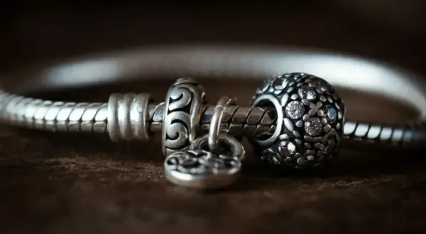 Srebrna bransoletka Pandora z charmsami, w tym charms z cyrkoniami i charms w kształcie serca.
