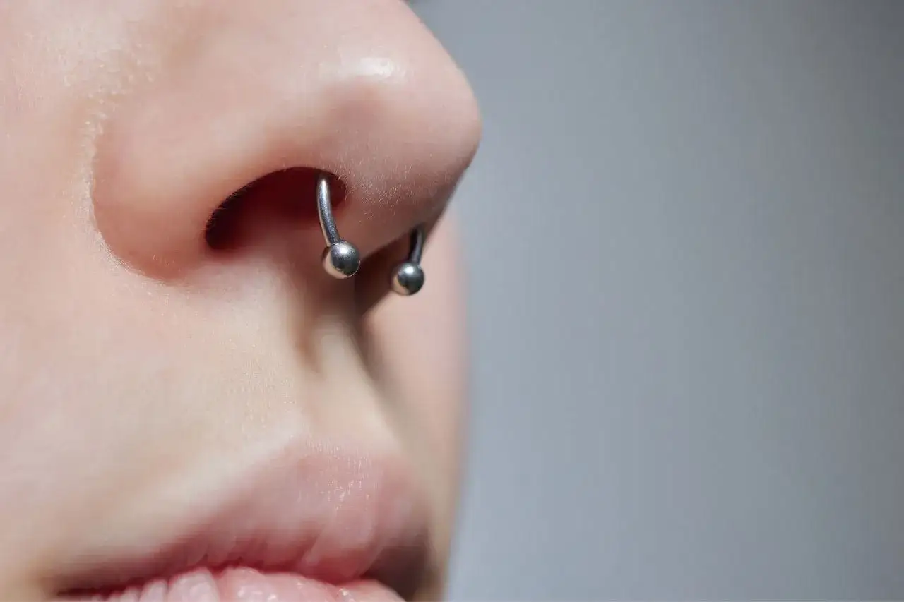 Metalowy kółko z kulkami w nosie. To jest septum, które zostało przekłute.
