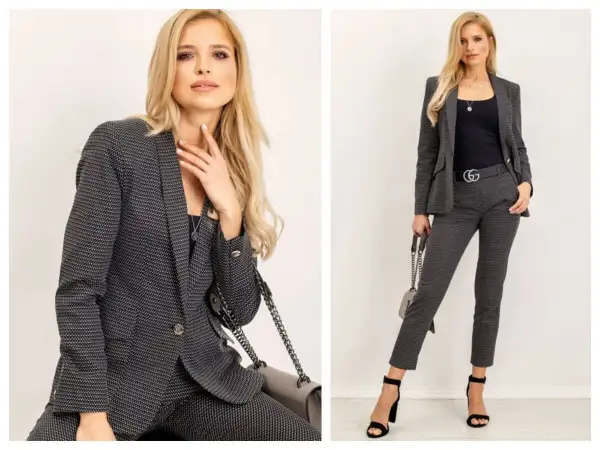 Elegancki damski casual dress code: kobieta w grafitowym garniturze w drobny wzór, z czarną bluzką i torebką.